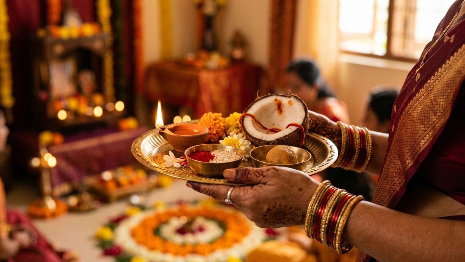 A sister applying a tilak to her brother’s forehead beside a decorated thali with a lamp, akshat and sweets on Bhai Dooj