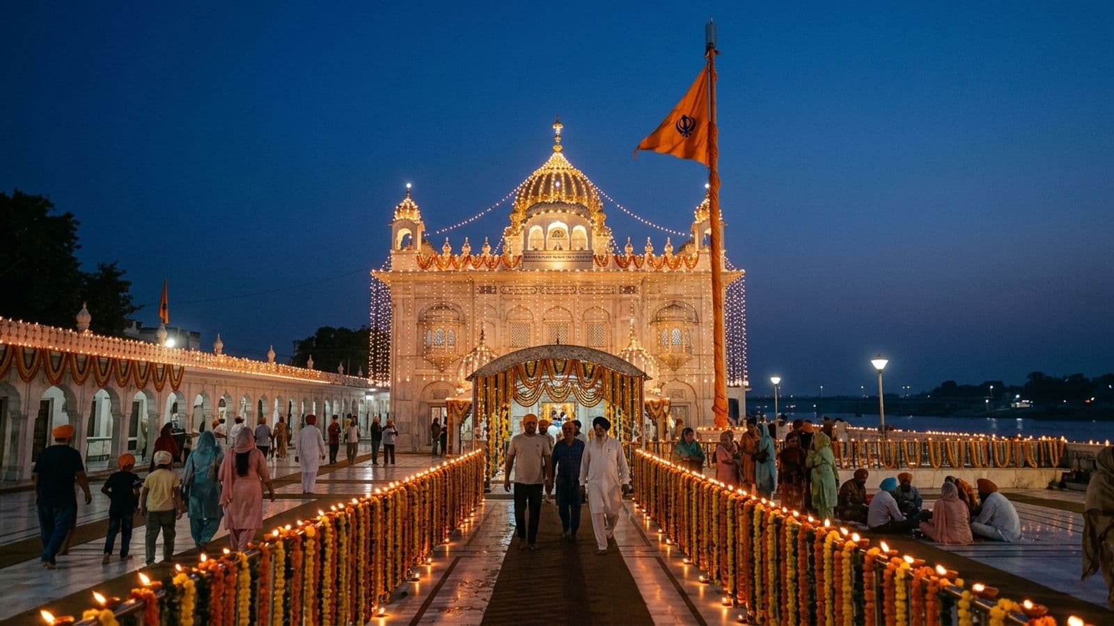 A gurdwara lit for Guru Nanak Jayanti with the Nishan Sahib, the Guru Granth Sahib and devotees at kirtan on the Prakash Utsav